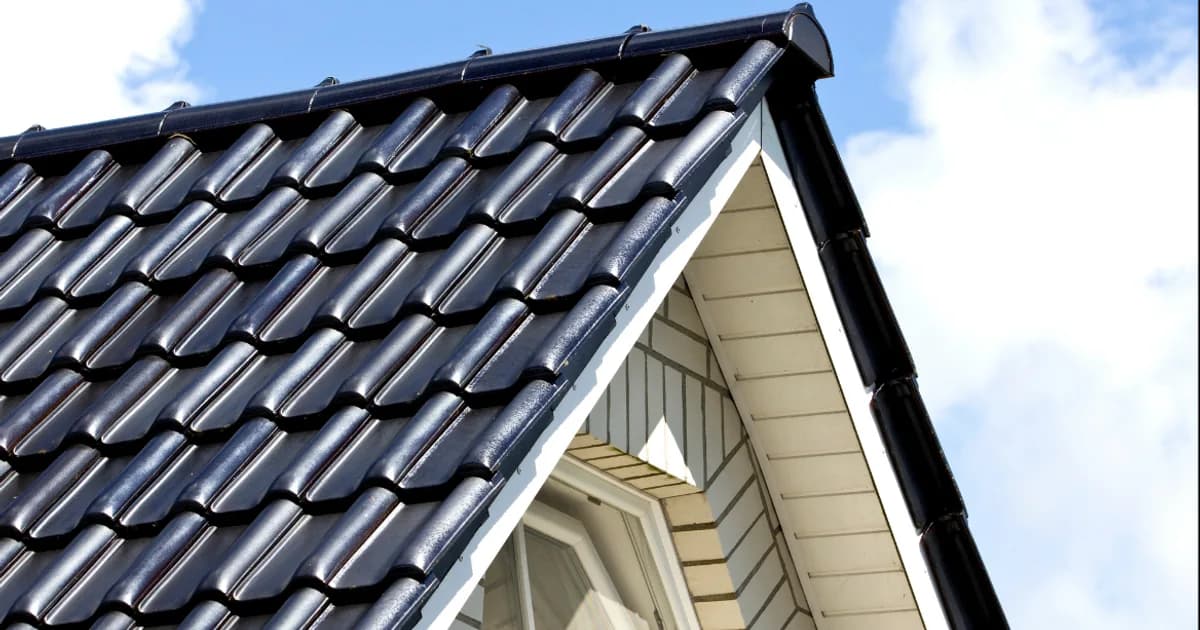 Steildach mit dunkler Ziegeleindeckung, Ortgang und Dachüberstand an einem Wohnhaus